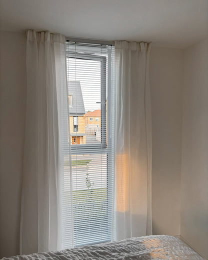 White custom sheer curtains with rod pocket top layered over window blinds, diffusing sunlight for a soft ambiance.