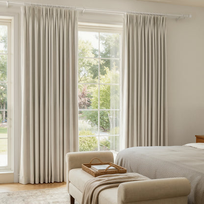Arden Satin Blackout Curtain: light beige pleated fabric in bright room with garden view.