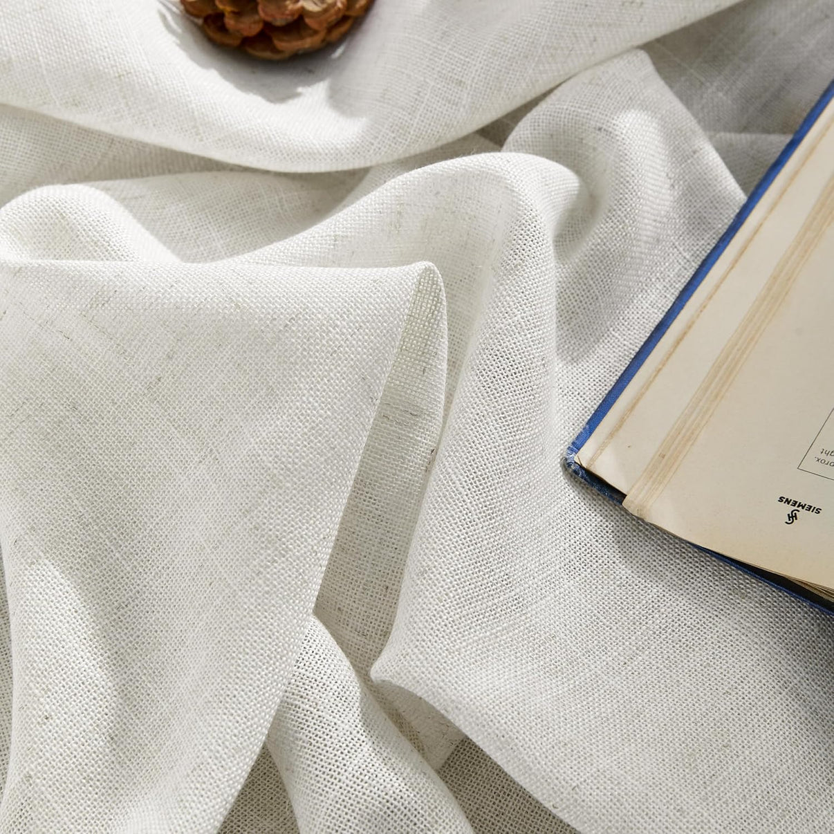 Close up of beige semi-sheer linen-blend curtain, textured weave, light filtering.