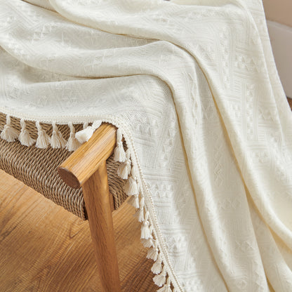 Close-up texture of Joydeco cream boho curtains featuring diamond pattern and cream tassels, draped over a woven chair.