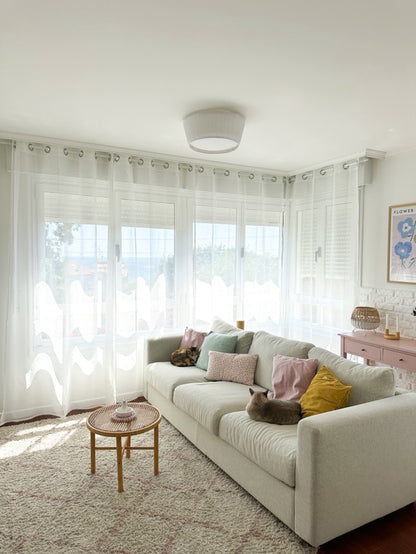 Joydeco white sheer curtains with rod pocket design in a living room, filtering sunlight onto a beige sofa with cats.