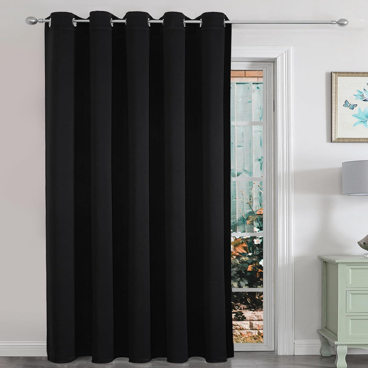 Black extra wide blackout curtain with grommets on a sliding glass door, used as a room partition.