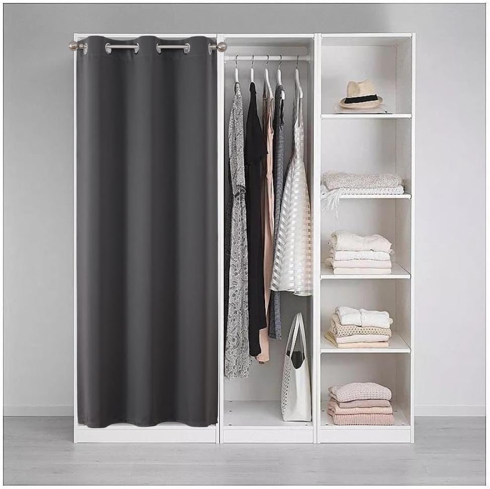 Grey blackout curtain with silver grommets used as a closet divider, concealing clothes and providing privacy in a bedroom.