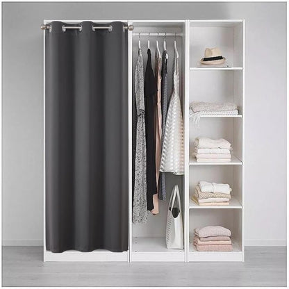 Grey blackout curtain with silver grommets used as a closet divider, concealing clothes and providing privacy in a bedroom.