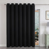 Black extra wide blackout curtain with grommets covers a sliding patio door, providing privacy and thermal insulation.
