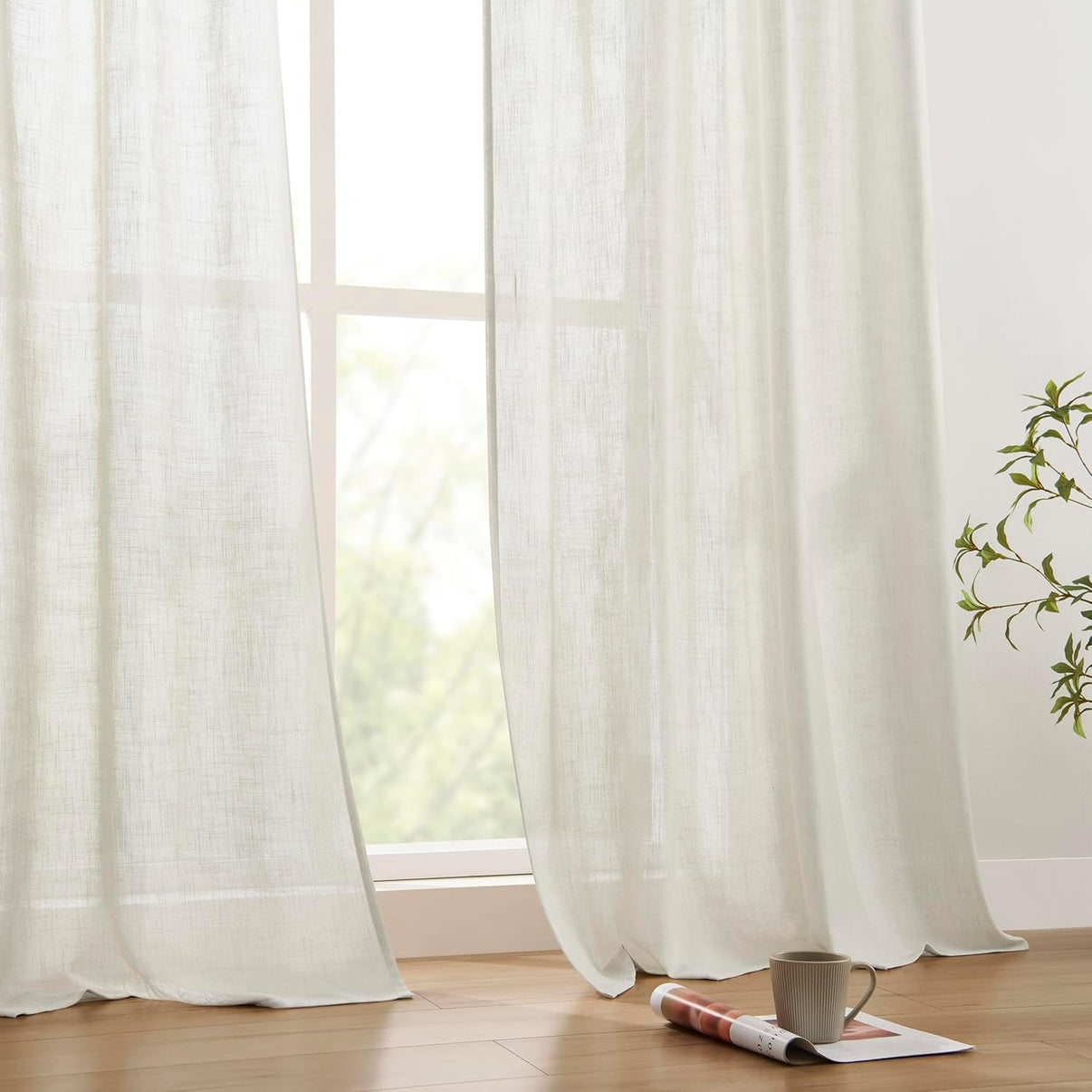 Joydeco natural linen blend curtains filtering light, showing texture. Magazine and mug on floor.