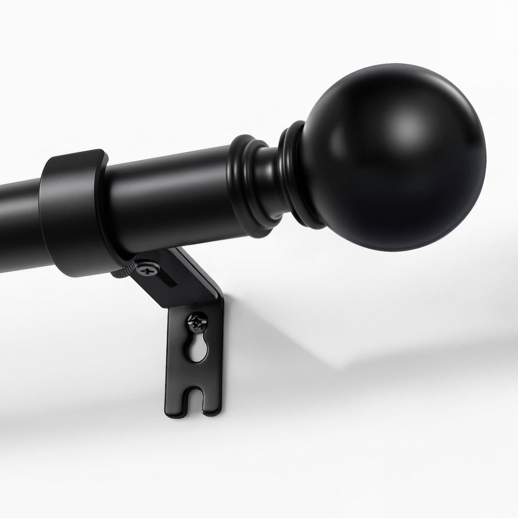 Joydeco matte black adjustable curtain rod, 1-inch diameter, with spherical finial, mounted on a white wall.
