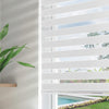 White Joydeco cordless zebra blinds with dual sheer and opaque stripes, filtering light from a backyard pool view.