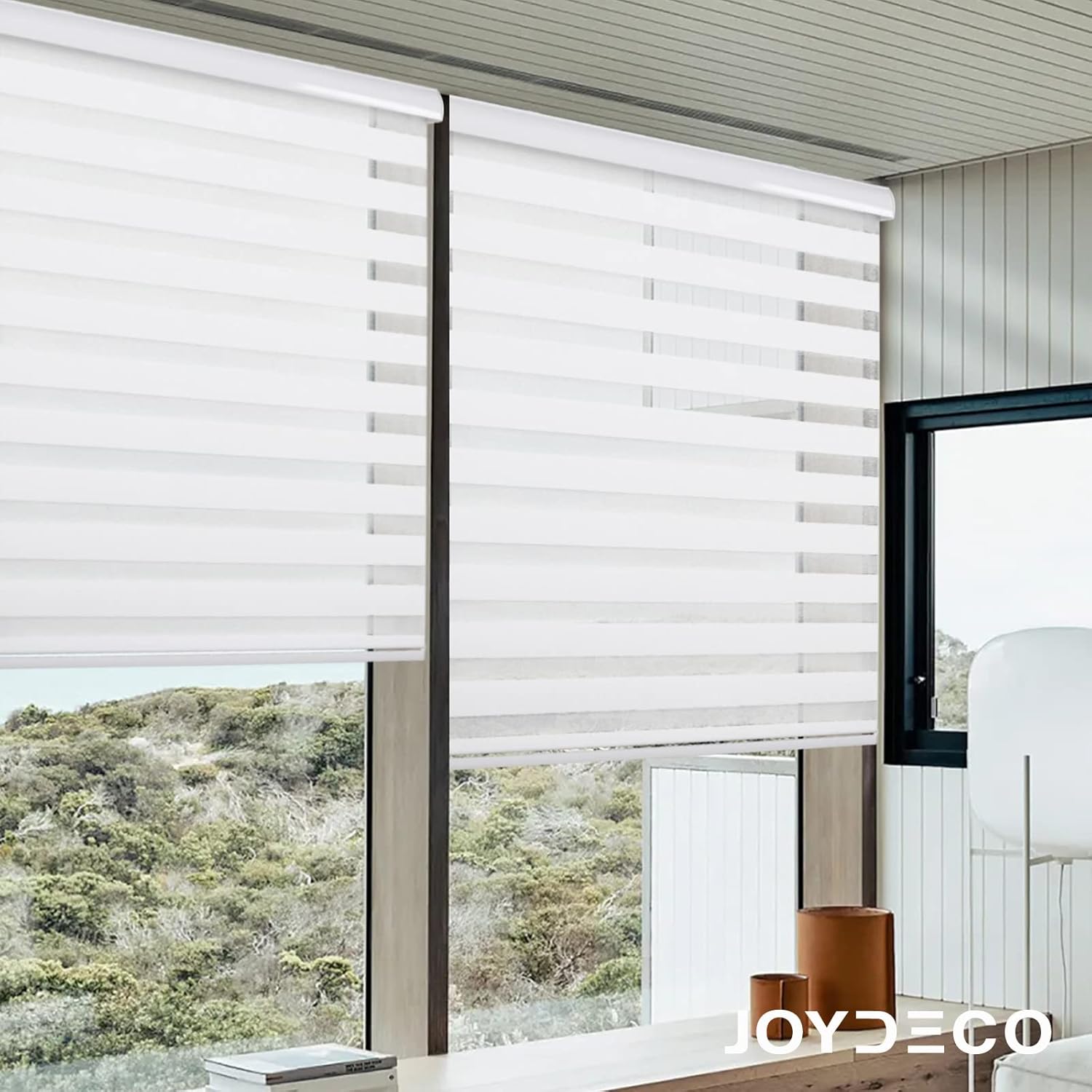 White Joydeco cordless zebra blinds with dual layer stripes filtering light across large windows with scenic landscape view.