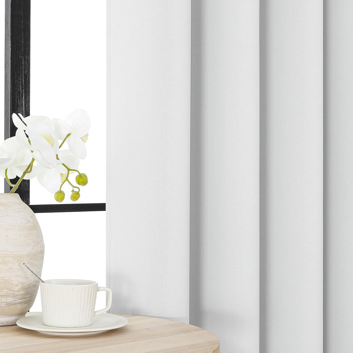 Joydeco white thermal blackout curtain with grommet top, styled in a cozy room with orchids.