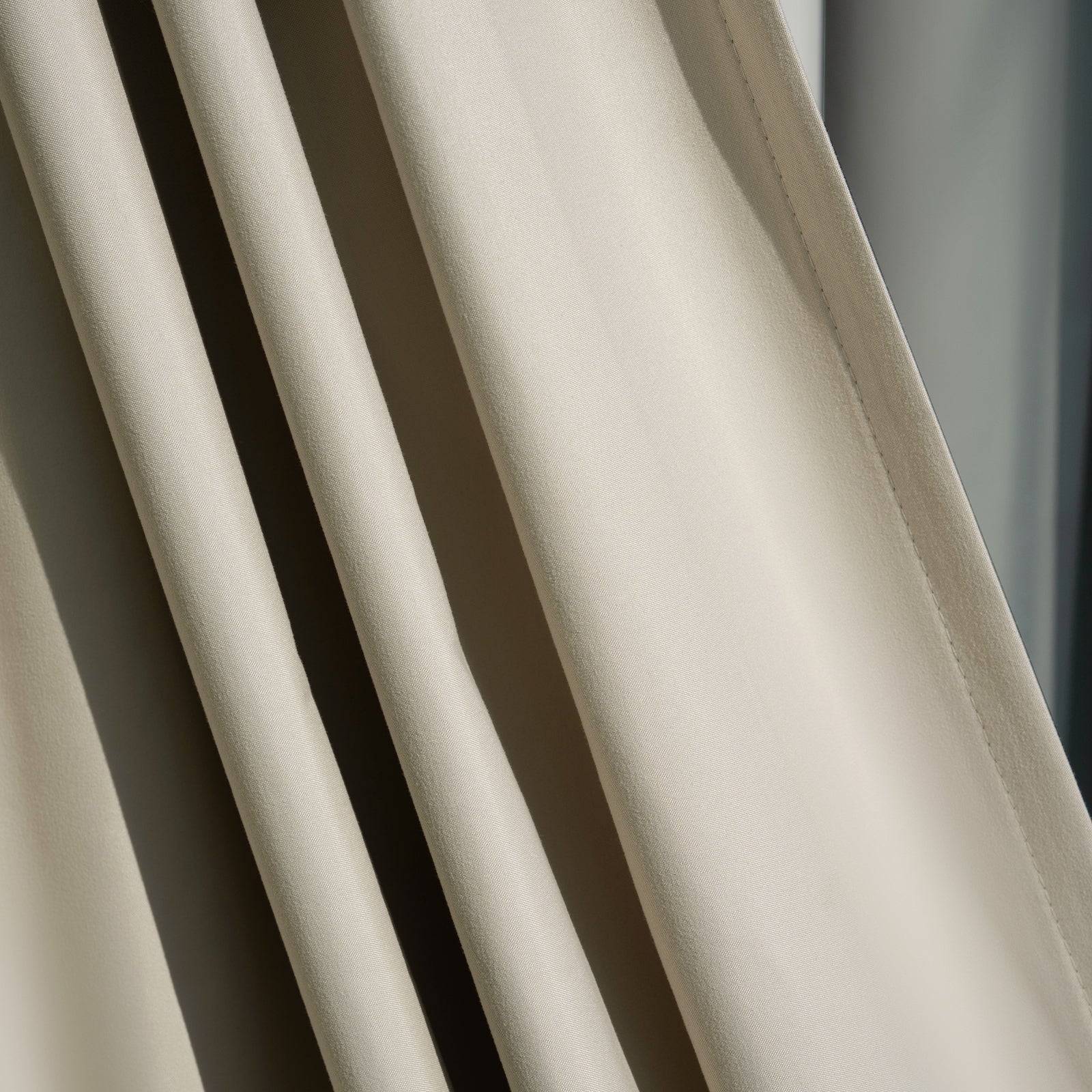 Arden satin blackout curtain fabric in light beige, smooth lustrous texture and elegant drape.