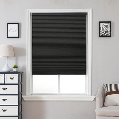 Black cordless blackout cellular shades, honeycomb design, shown on window in room.