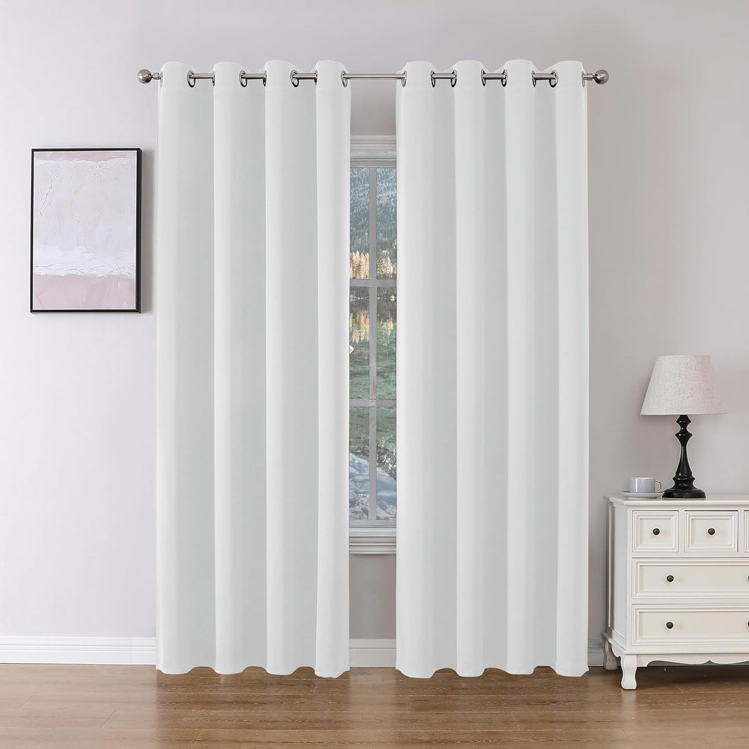 Two white Joydeco floor-length blackout curtains with grommet tops hang on a silver rod in a room setting.