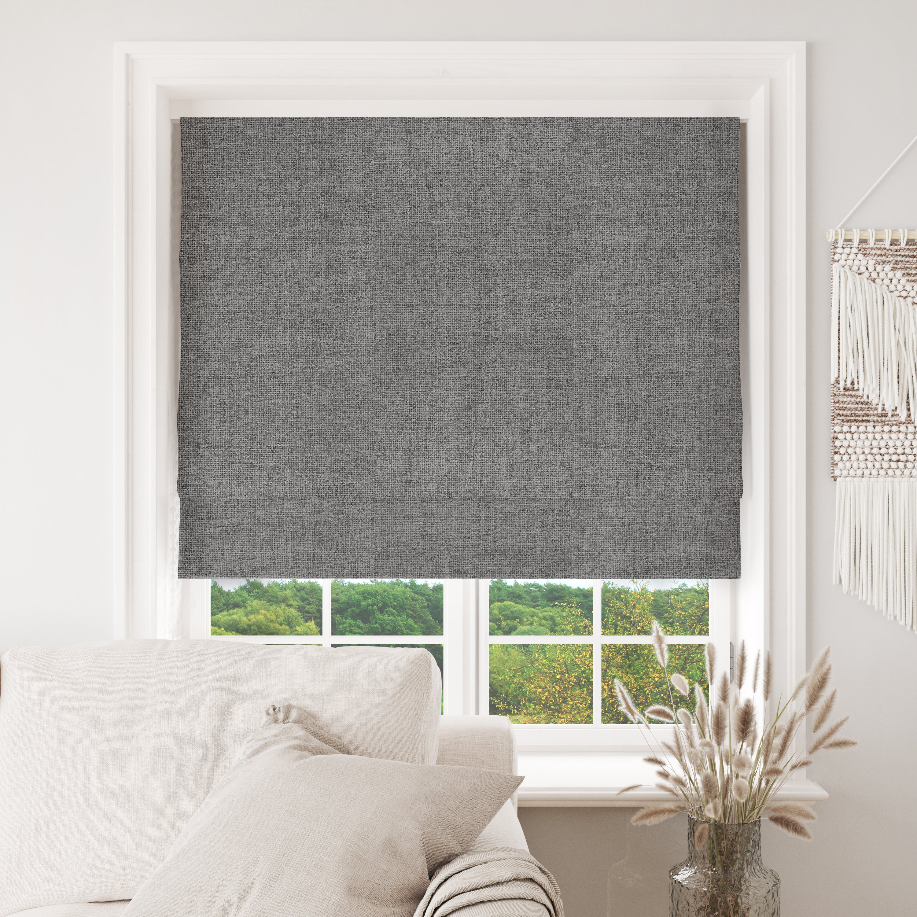 Grey Joydeco custom blackout Roman shade partially lowered in a white window, showcasing fabric texture and light control.
