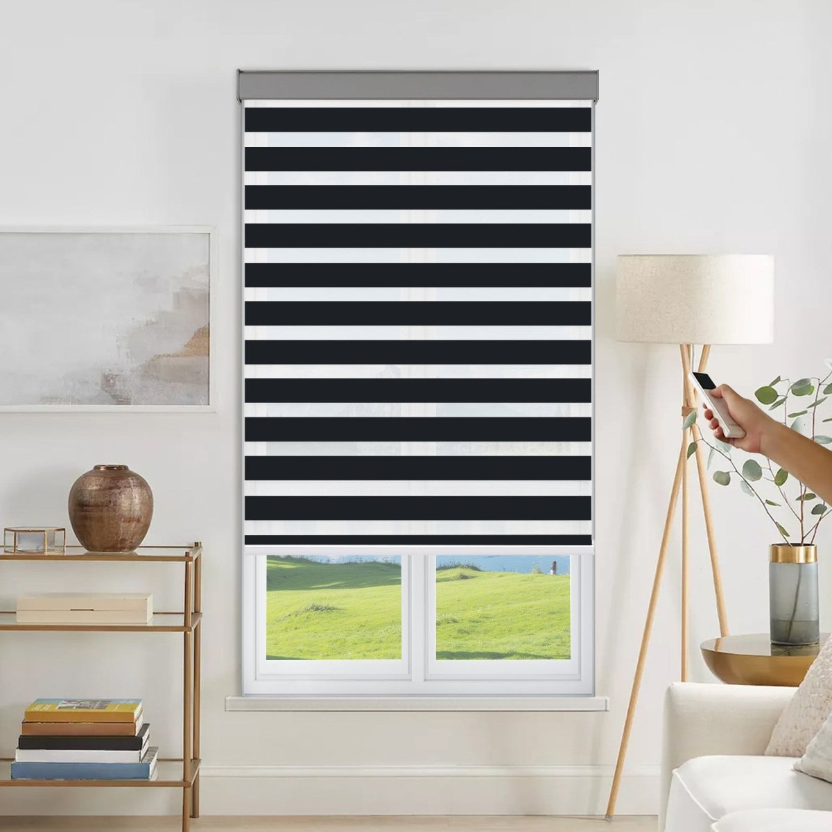 Joydeco motorized black and white striped dual shade with grey valance on window, hand holding remote for operation.