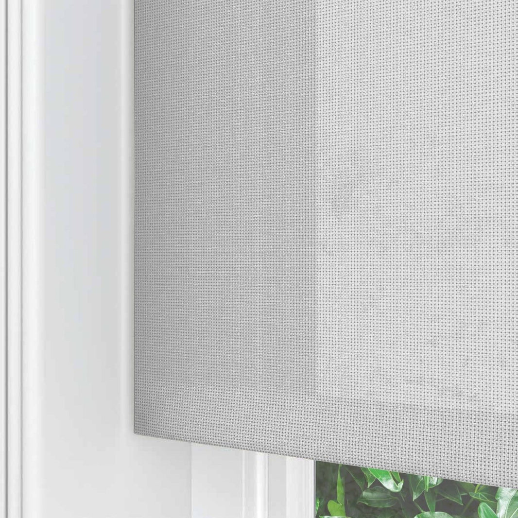 Close-up of Joydeco light grey sheer weave solar shade with visible texture, inside a white window frame, partially lowered.