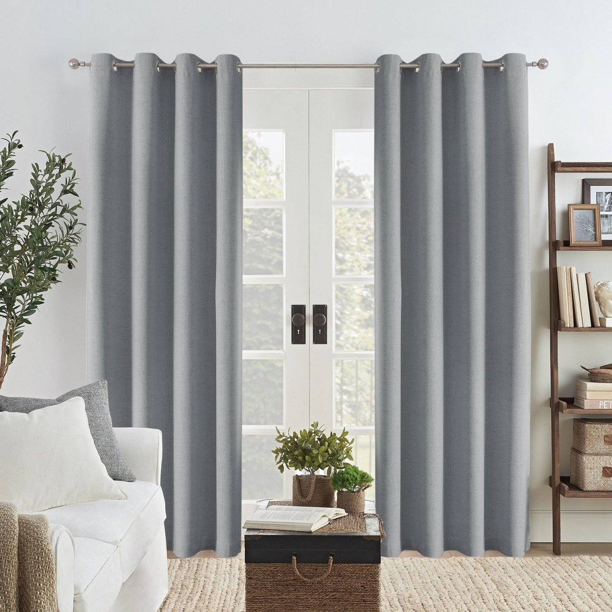 Light grey Joydeco linen blackout curtains with grommets hanging on a double door, adding texture to a living room.