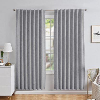 Grey linen blackout curtains with back tab rod pocket style in a modern bedroom, showing pleated drape and texture.