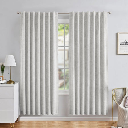 Light gray linen blackout curtains with back tab rod pocket hanging from silver rod in a modern bedroom.