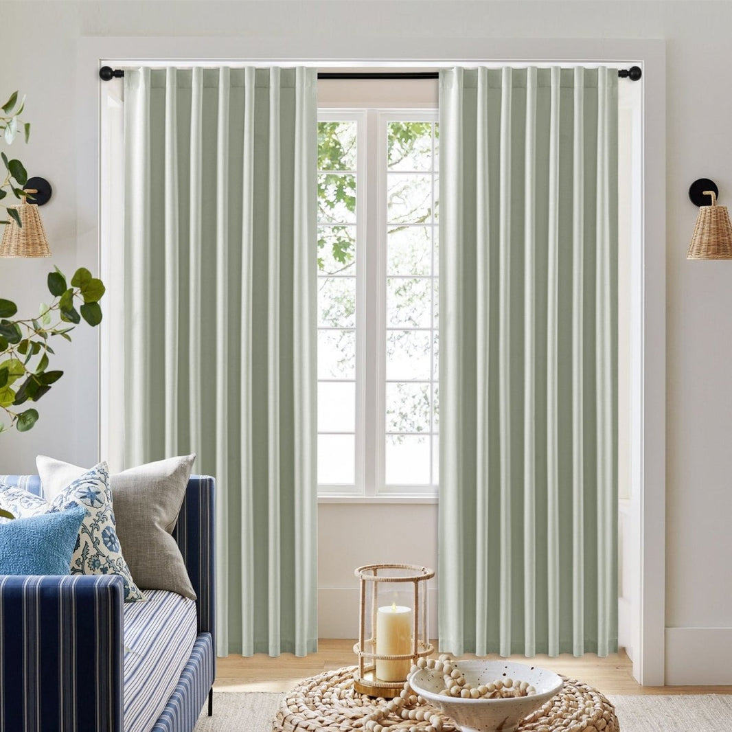 Light sage faux linen blackout curtains with black grommets, elegant drape in living room setting with blue sofa.