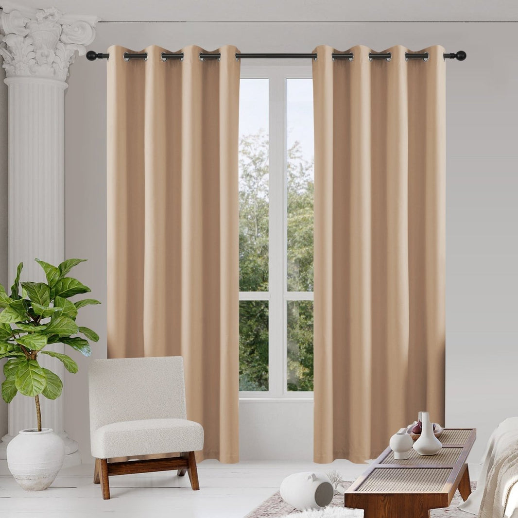 Joydeco beige blackout curtains, two thermal insulated panels hanging in a room with armchair and coffee table.