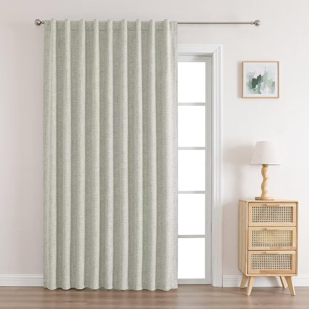 Long beige linen blackout curtain with metal grommets covering a door, showcasing textured weave and elegant pleats.