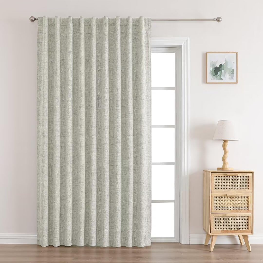 Long beige linen blackout curtain with metal grommets covering a door, showcasing textured weave and elegant pleats.