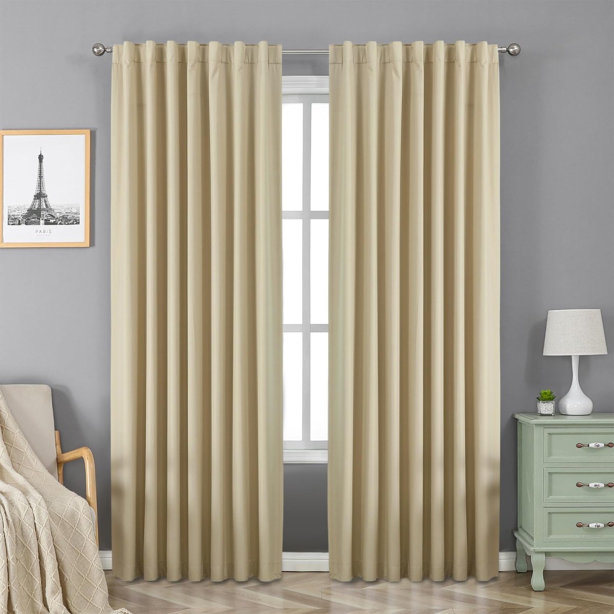 Two beige faux linen 100% blackout curtains with rod pocket, hanging on a window in a room with grey walls.