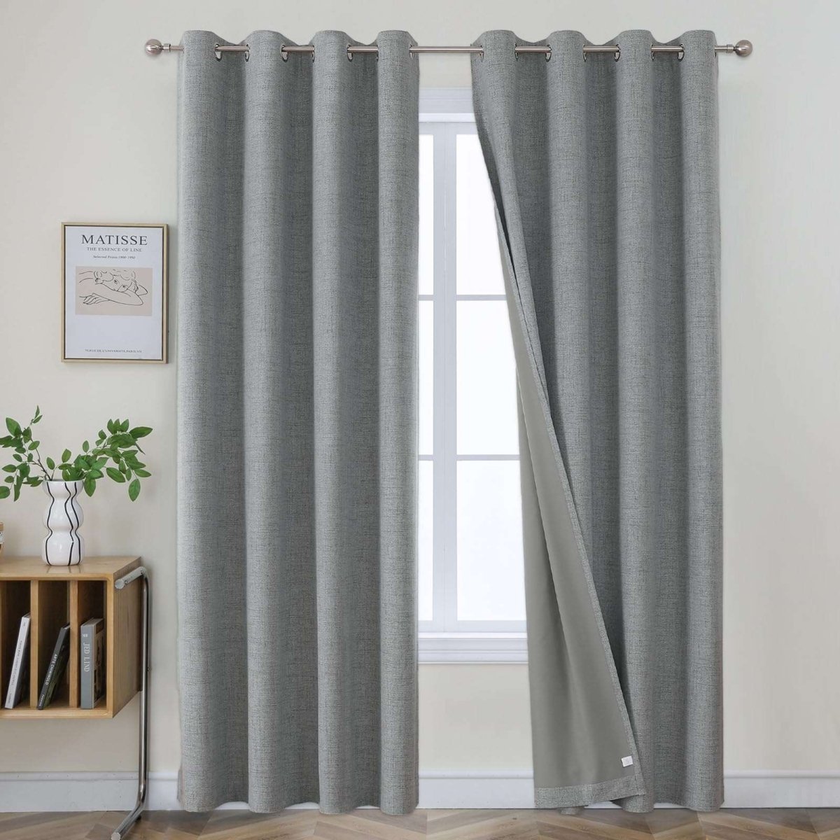Two light grey textured linen blackout curtain panels with metal grommets displayed on a silver rod.