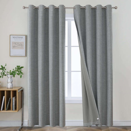 Two light grey textured linen blackout curtain panels with metal grommets displayed on a silver rod.