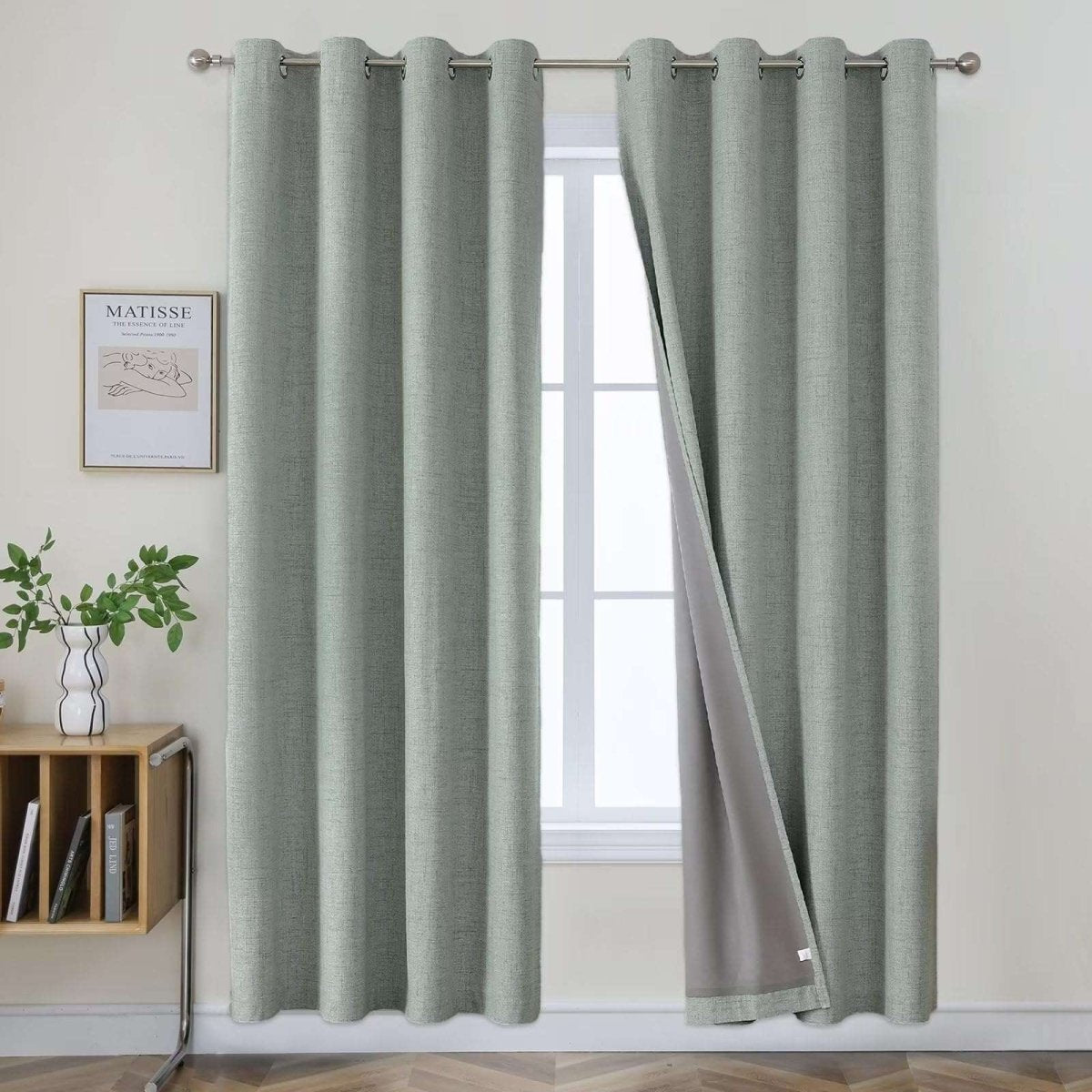 Two sage green textured linen blackout curtain panels with grommet tops, showcasing 100% blackout feature.
