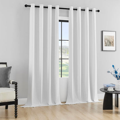 Two white Joydeco 100% blackout curtains with grommets, displayed in a modern room setting.