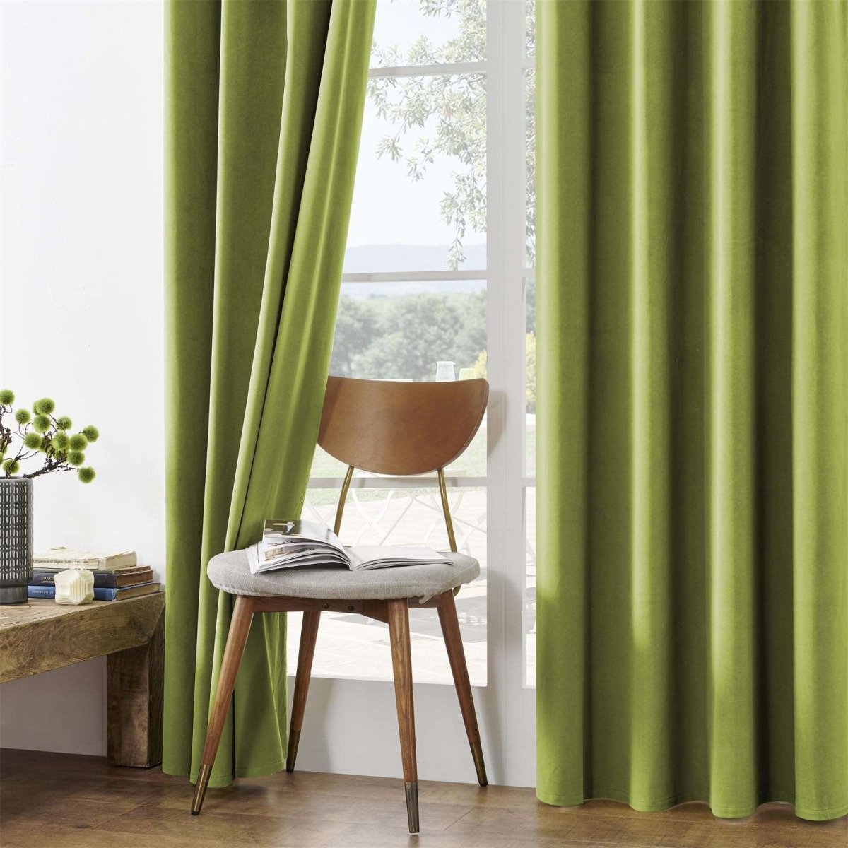 Joydeco olive green velvet blackout curtains draped beside a window with a wooden chair. Product page style.
