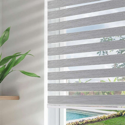 Grey blackout zebra shades with dual light filtering layers, showing view of pool and garden through window.