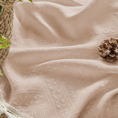 Close-up of light pink boho linen sheer curtain fabric with diamond pattern and cream fringe detail.