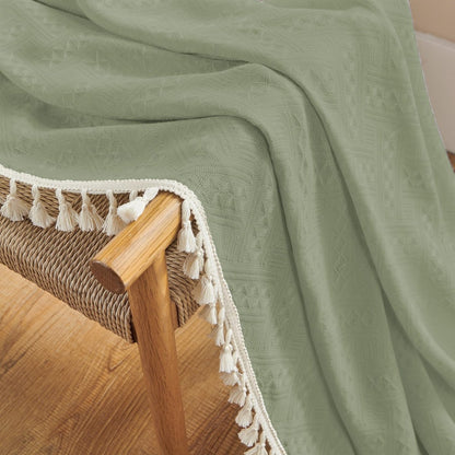 Sage green linen curtains with cream tassels and subtle geometric pattern, boho farmhouse texture detail.