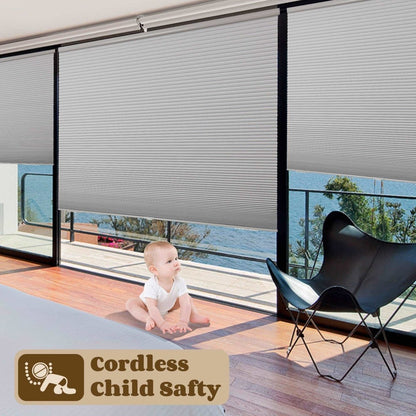 Light grey cordless cellular shades protecting a baby from potential hazards on the floor, emphasizing child safety.