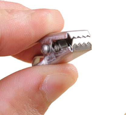 Joydeco small stainless steel clip with serrated grip and spring, shown by fingers for scale.