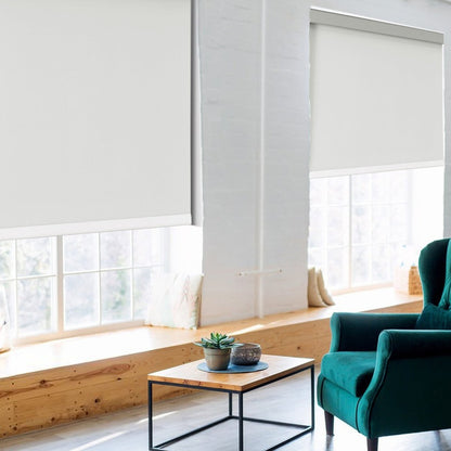 Joydeco white blackout roller shades in a room with green armchair and coffee table.