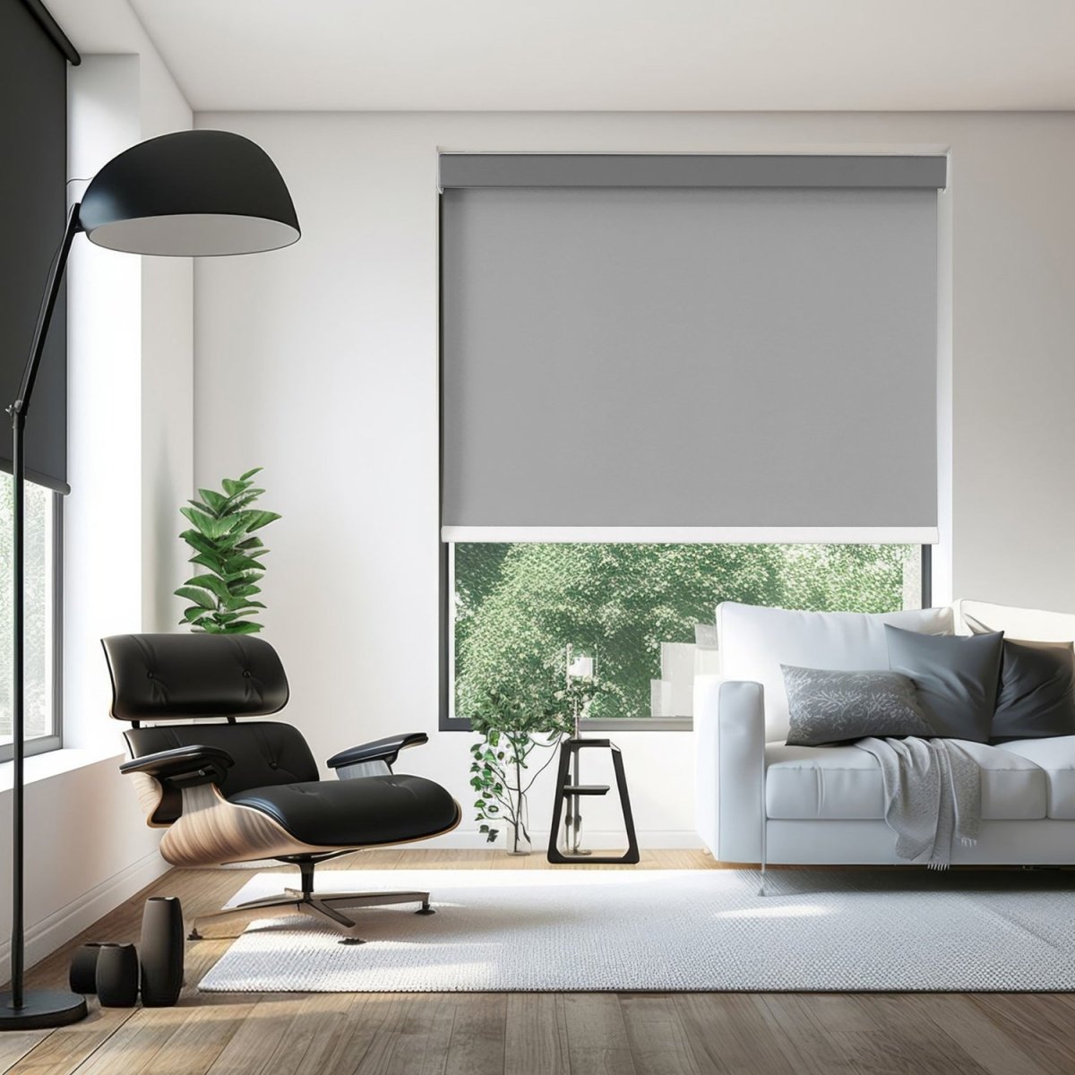 Joydeco grey cordless blackout roller shade partially lowered in a living room with a black armchair and white sofa.