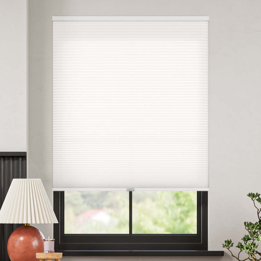 White cordless light filtering cellular shade with honeycomb texture, partially open on window.