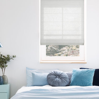 Joydeco off-white linen blend Roman shade with horizontal pleats filters light in a bedroom.