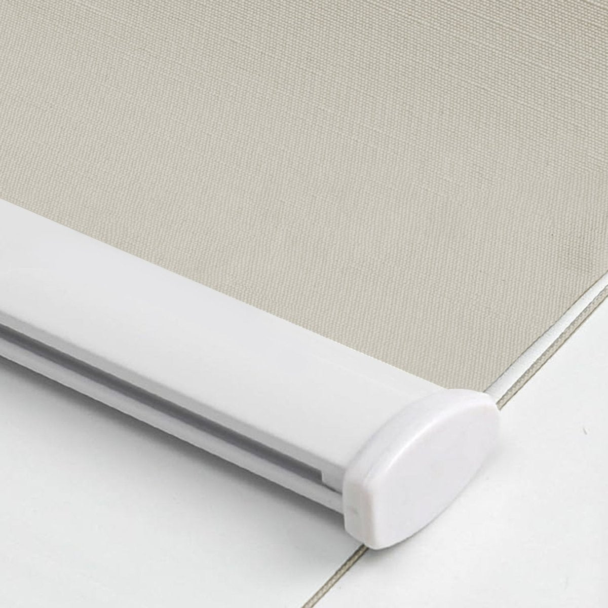 Close-up of light beige woven blackout roller shade fabric texture with white aluminum bottom bar and end cap.
