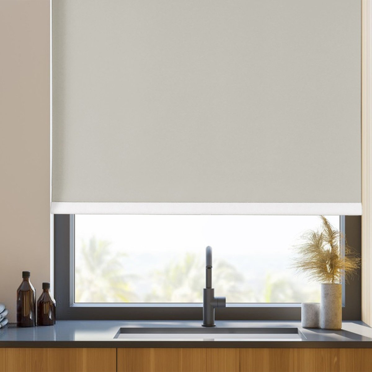 Joydeco custom cordless blackout roller shade in light cream, installed in a modern kitchen over a sink.