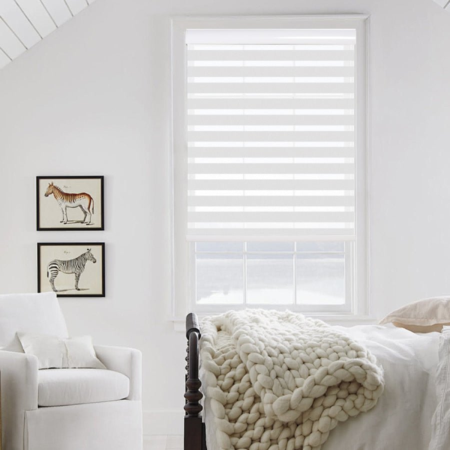Modern white dual zebra shade with light filtering stripes mounted on a white window in a bedroom.