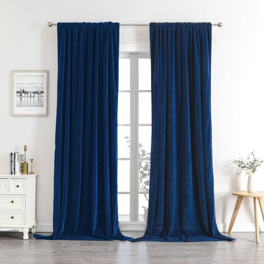 Deep navy velvet blackout curtains with plush texture, shown in a room setting framing a window.