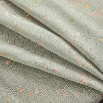 Close-up of beige linen sheer curtain fabric with small pink and yellow floral pattern, showing texture.