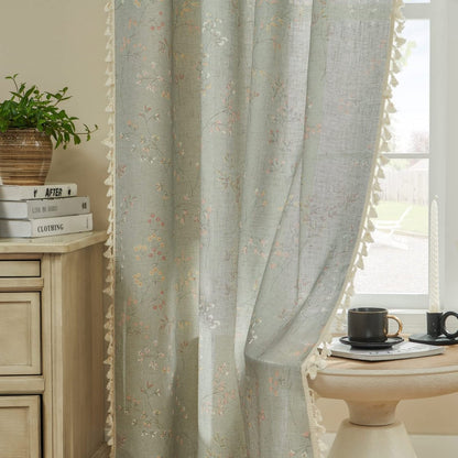 Light blue linen sheer curtains with floral embroidery, cream tassel trim, and visible texture.