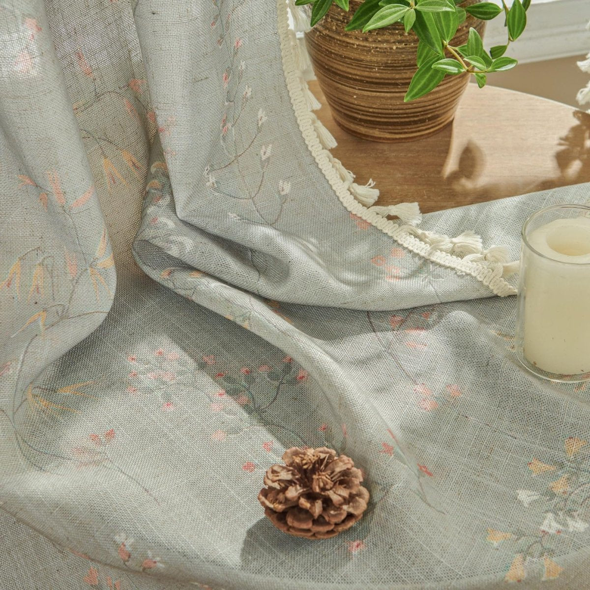 Light blue linen sheer curtain with floral embroidery and cream tassel trim, product detail.