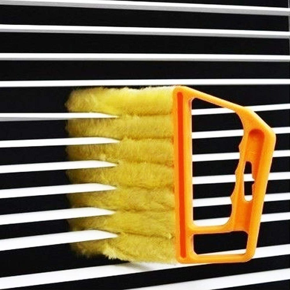 Joydeco handheld blinds cleaner with orange handle and yellow brush cleaning black and white horizontal blinds slats.